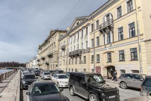 una concurrida calle de la ciudad con coches estacionados frente a los edificios en Апартаменты Веста на Фонтанке, en San Petersburgo