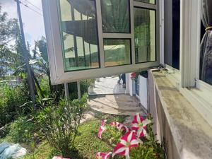 una ventana en una casa con flores en el patio en Rania Lovely Hut Homestay Kundasang en Kampong Kundassan