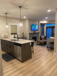 a kitchen with a sink and a living room at Cozy Modern Ski-in/Ski-out, Hot Tub, Alpine Home in Sun Peaks