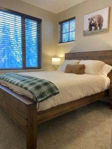 a bedroom with a large bed and two windows at Cozy Modern Ski-in/Ski-out, Hot Tub, Alpine Home in Sun Peaks