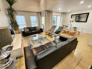 a living room with a leather couch and a table at Spacious 4 BR and 2 Bathrooms City Apartment in Adelaide