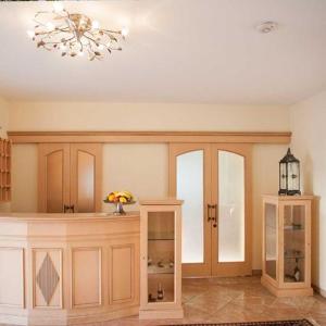 a living room with a chandelier and a room with cabinets at Hotel Egger-Stüberl in Schechen