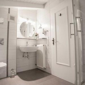 La salle de bains blanche est pourvue d'un lavabo et d'un miroir. dans l'établissement Hotel Egger-Stüberl, à Schechen
