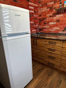 a white refrigerator in a kitchen with a brick wall at Комфортабельная однокомнатная квартира in Balqash