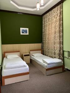 2 łóżka w pokoju z zielonymi ścianami w obiekcie Гостиница Селена w Kyzyłordzie