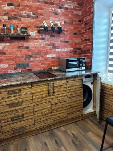 a kitchen with a microwave and a brick wall at Комфортабельная однокомнатная квартира in Balqash