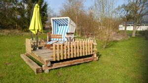 a wooden deck with a chair and an umbrella and a table at boddenbackpacker in Bartelshagen