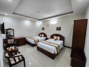 a hotel room with two beds and a mirror at Marguerite Dalat Hotel in Da Lat