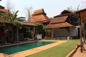 a swimming pool in the yard of a house at Capital O 75421 Baan Singkham Boutique Resort in Chiang Mai