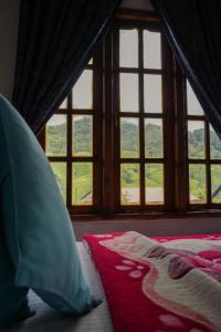 a bedroom with a bed and a window with a view at The Train View in Nuwara Eliya