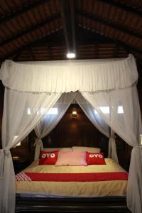 1 dormitorio con cama con dosel y almohadas rojas en Capital O 75421 Baan Singkham Boutique Resort, en Chiang Mai