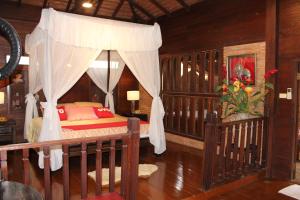 a bedroom with a canopy bed and a crib at Capital O 75421 Baan Singkham Boutique Resort in Chiang Mai