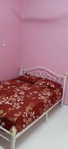 ein Schlafzimmer mit einem Bett mit einer braun-goldenen Tagesdecke in der Unterkunft BONDA HOMESTAY in Kampung Gurun