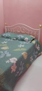 ein Bett mit einer grünen Decke mit Blumen drauf in der Unterkunft BONDA HOMESTAY in Kampung Gurun