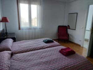 1 dormitorio con 2 camas, silla y espejo en Casa Korrontxas & Ega Txokoa, en Murieta