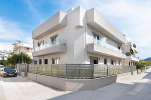 un edificio bianco con una recinzione di fronte di 30 Senses Luxury Apartment Insight a Ialyssos