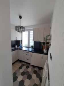a kitchen with white cabinets and a checkered floor at Apartament Przy Ratuszu in Malbork