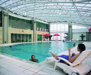 two women laying in chairs in a swimming pool at Suning Universal Hotel ALL-SUITES in Nanjing