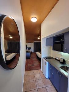 a kitchen with a mirror and a living room at City of Sails Motel in Auckland