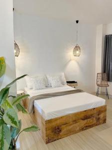 - une chambre dotée d'un lit en bois avec des draps et des oreillers blancs dans l'établissement New Modern Suite Near Airport & Beach, à Sudtungan