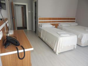 トラブゾンにあるSogutpark Hotelのベッド2台、電話、デスクが備わる客室です。