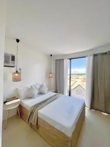 - une chambre blanche avec un grand lit et une fenêtre dans l'établissement New Modern Suite Near Airport & Beach, à Sudtungan