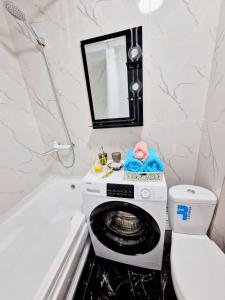a bathroom with a washing machine next to a bath tub at НОВАЯ - 1 комнатная квартира! in Taraz