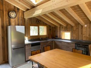 a kitchen with a table and a stainless steel refrigerator at chalet du Champel jacuzzi in Saint-Gervais-les-Bains