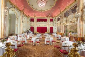 a banquet hall with white tables and red chairs at Grand Hotel Bohemia in Prague