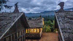 due tetti di case con vista sulle montagne di The Asaro Mudmen Tribal Eco Lodge 