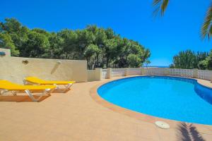a swimming pool with two yellow chairs and a swimming pool at NEO - sea view villa with private pool in Moraira in Teulada