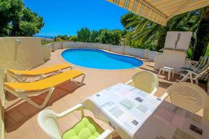 a patio with a table and chairs and a pool at NEO - sea view villa with private pool in Moraira in Teulada