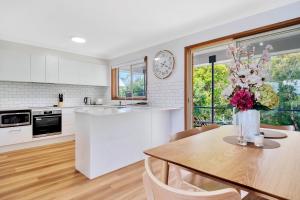 a kitchen with a table and a vase of flowers at Bateau Family Retreat - Magical sunset views in Bateau Bay