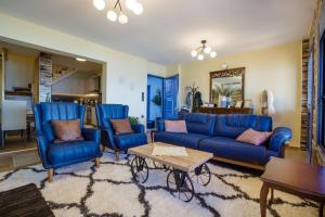 una sala de estar con sofás azules y una mesa. en Maritinas Stone House & Apartment On The Beach - Happy Rentals, en Katakolon