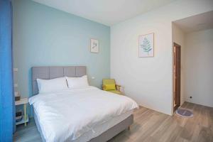 1 dormitorio con cama blanca y pared azul en Meedori Coffee Home Stay, en Hou-feng-kang