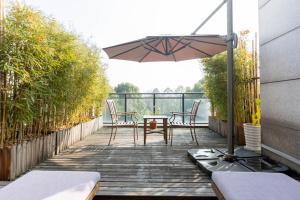 eine Holzterrasse mit einem Tisch und einem Sonnenschirm in der Unterkunft Xixi Nanlu Ssaw Boutique Hotel in Hangzhou