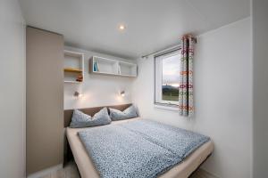 a small bedroom with a bed and a window at KNAUS Campingpark Oyten in Oyten