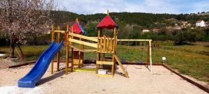 a wooden playground with a slide and a slideintend at Krka Fairytale village in Rupe