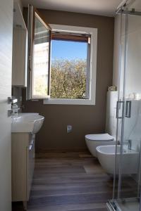 a bathroom with a sink and a toilet and a window at Appartamenti Del Borgo in Borgosesia
