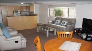 a living room with a couch and a table at Norfolk Grove Apartment - Hosted by Burleigh Letting in Gold Coast