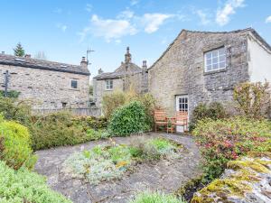 an old stone house with a bench in the garden at Victoria Cottage in Kettlewell