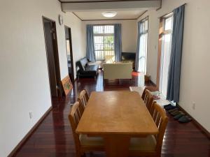 a dining room with a wooden table and chairs at 一棟貸しの宿 民宿せいじん家 in Miyako-jima