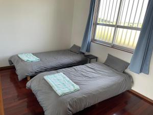 2 camas individuales en una habitación con ventana en 一棟貸しの宿 民宿せいじん家 en Isla Miyako
