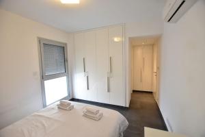 a white bedroom with two towels on a bed at Glabur Stays - The Amazing 1 BDR - Executive apt Nicosia Center Free Parking & WiFi in Nicosia