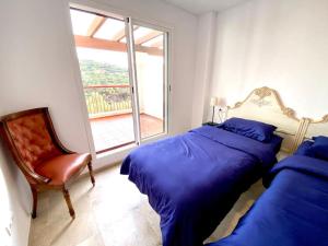 1 dormitorio con 2 camas, silla y ventana en Apartment Alcaidesa en Alcaidesa