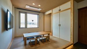 高山市にあるHotel and Spa Gift TAKAYAMAのテーブルと椅子、窓が備わる客室です。