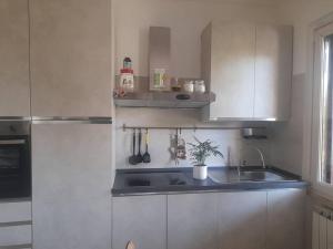 una cocina con armarios blancos y fregadero en casa nel bosco, en Bella Farnia