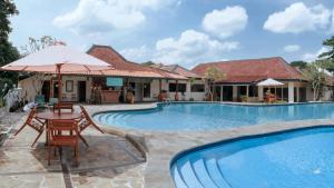 a villa with a swimming pool and a table with an umbrella at Royal Brongto Hotel in Timuran