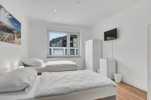 een witte kamer met 2 bedden en een raam bij 3-room apartment in Bochum