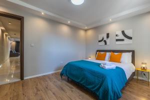 een slaapkamer met een bed met blauwe lakens en oranje kussens bij Brand New Modern 2 Bed Apt St Julians in St Julian's